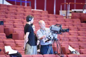 people looking into a stage camera with raked seating behind