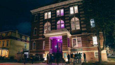 outside of arts building at night with people milling around