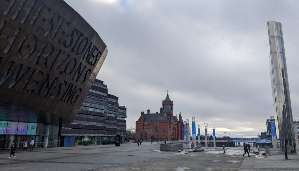 Wide plaza view showing Millennium Centre, historic Pierhead Building, and modern waterfront development in Cardiff Bay
