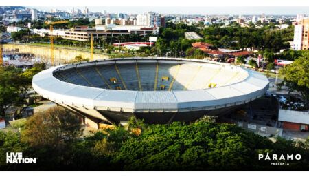 large open-roof arena in urban landscape with trees