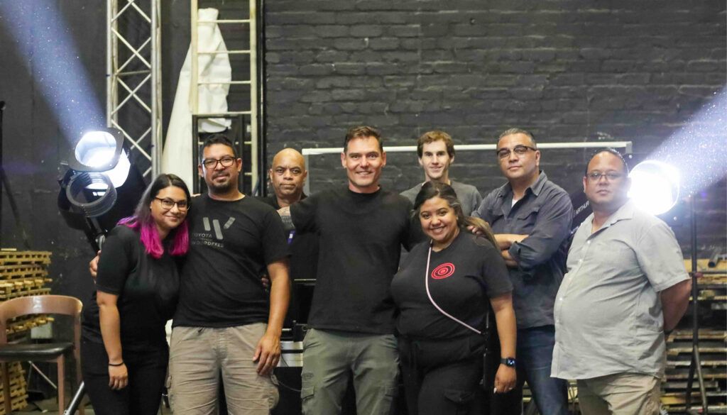 Group photo of eight people posing together with equipment backdrop