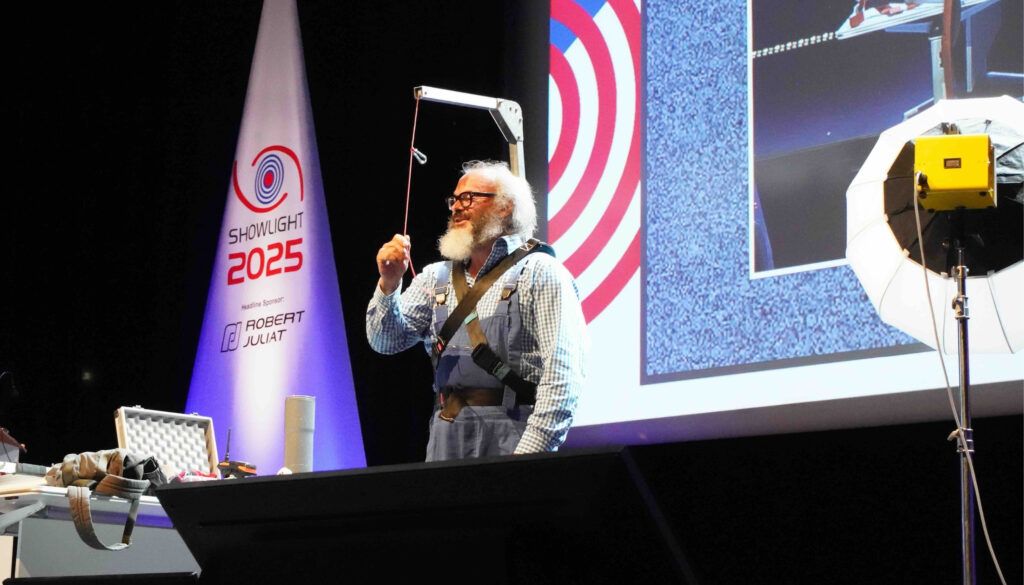 Presenter demonstrating equipment on stage at Showlight 2025 conference