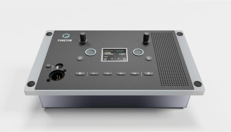 Professional audio intercom control panel with two knobs, buttons, display screen, speaker grille, and connector on silver chassis