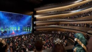 Modern concert hall interior with curved tiered seating and blue-lit stage performance
