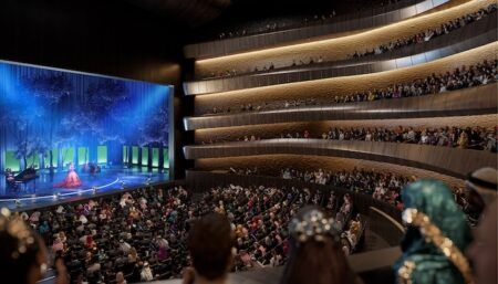 Modern concert hall interior with curved tiered seating and blue-lit stage performance
