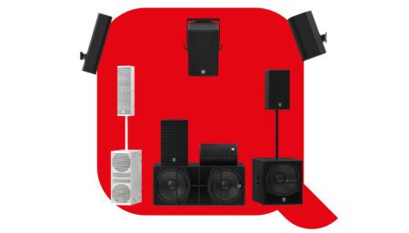 Collection of black and white professional audio speakers and subwoofers arranged on red background