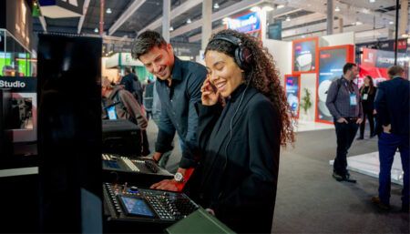Two people testing audio equipment at exhibition booth