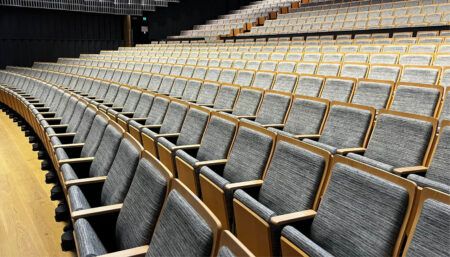 Tiered auditorium seating with grey upholstery and orange accents