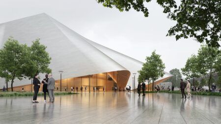 Wide-angle exterior view of The Opera & Ballet Theatre of Kosovo showing the building's curved entrance structure beneath a sweeping white geometric roof, surrounded by trees and visitors on a reflective paved plaza.