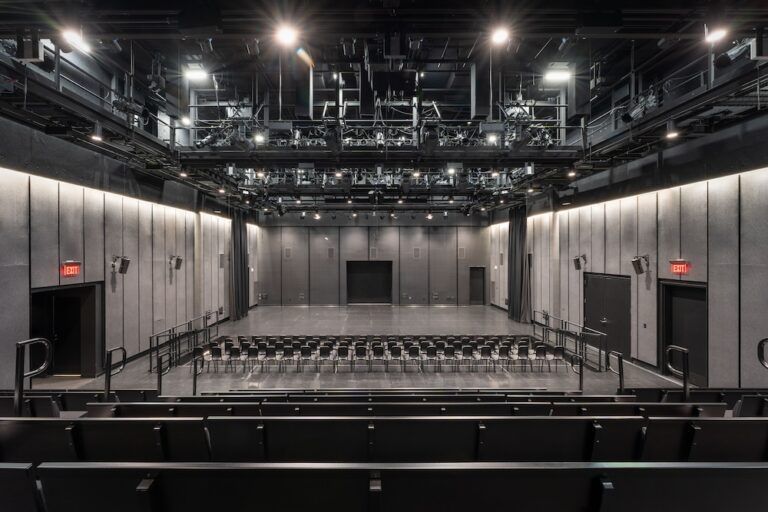 Meyer Sound installation at Woodruff Arts Center’s Goizueta Stage Interior of a flexible black-box theatre with raked seating at the rear and flat-floor seating at the front, viewed from the upper level, with an overhead grid of stage lighting.